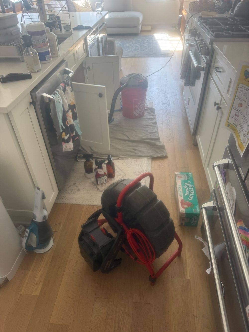 A drain machine and a hose reel standing ready in the corner of a tiled interior.