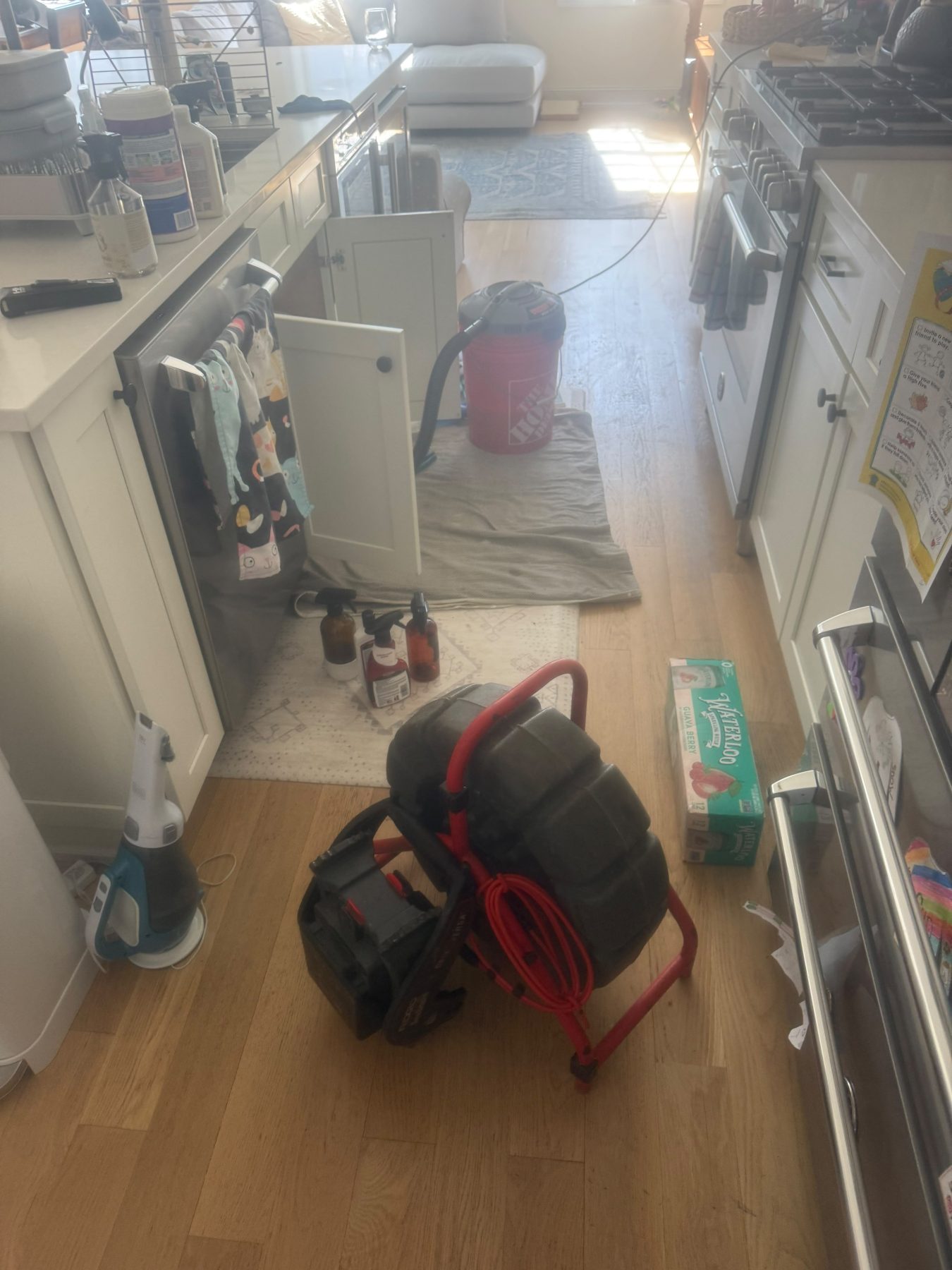 A drain machine and a hose reel standing ready in the corner of a tiled interior.