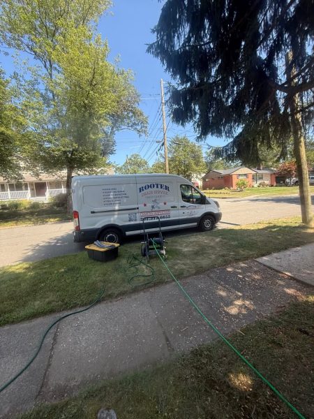 The van at the kerb on a residential street with the hose run across the verge toward the house.