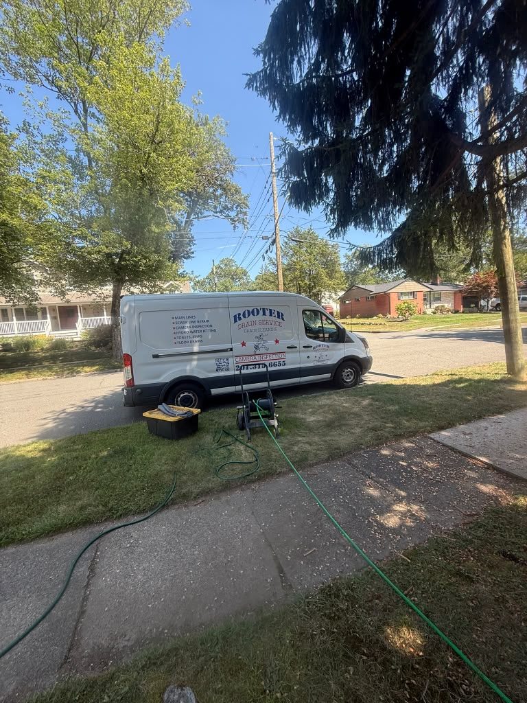The van at the kerb on a residential street with the hose run across the verge toward the house.
