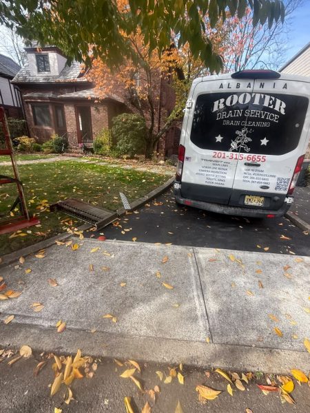 The van parked in a driveway with the hose run up to the house, autumn leaves on the ground.