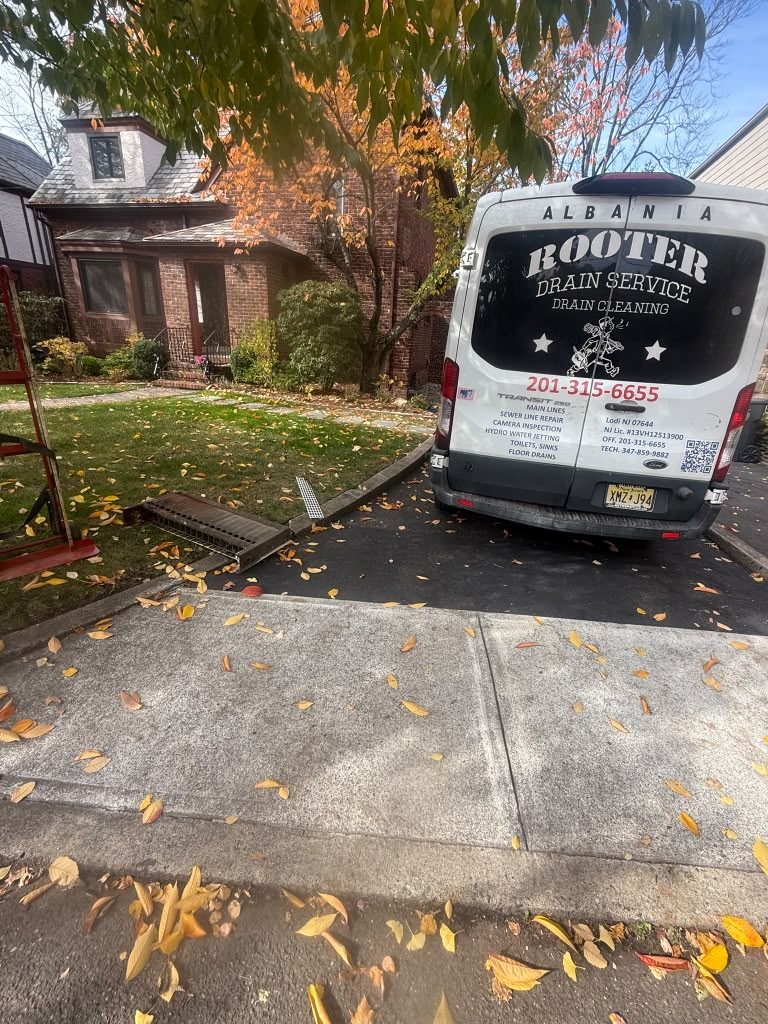 The van parked in a driveway with the hose run up to the house, autumn leaves on the ground.