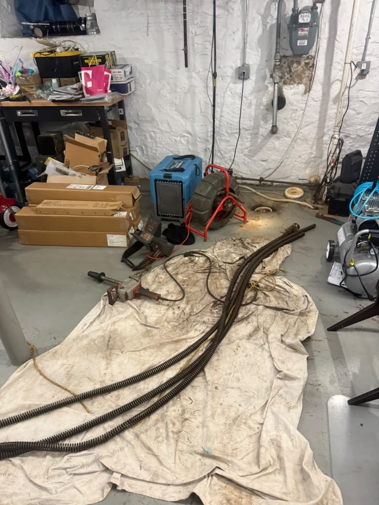 Hoses laid out across protective sheeting on a basement floor, with equipment staged against the wall.
