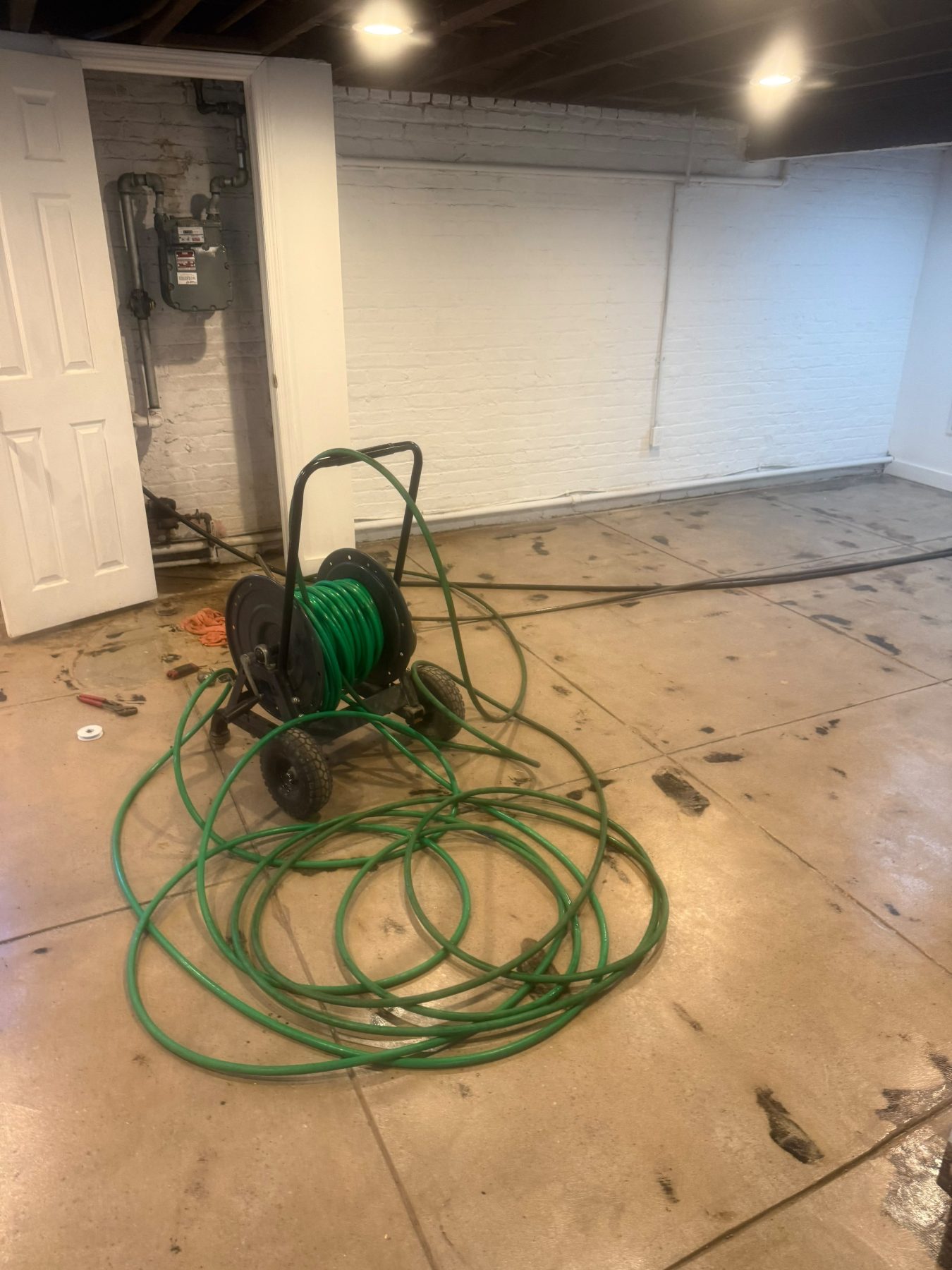 A coiled high-pressure hose on the floor of an interior space, ready for use.