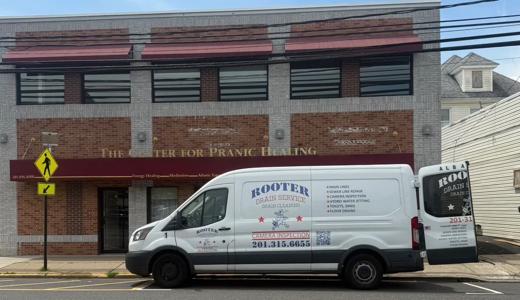 The Rooter Drain Service van parked on the street outside a red-brick commercial building.